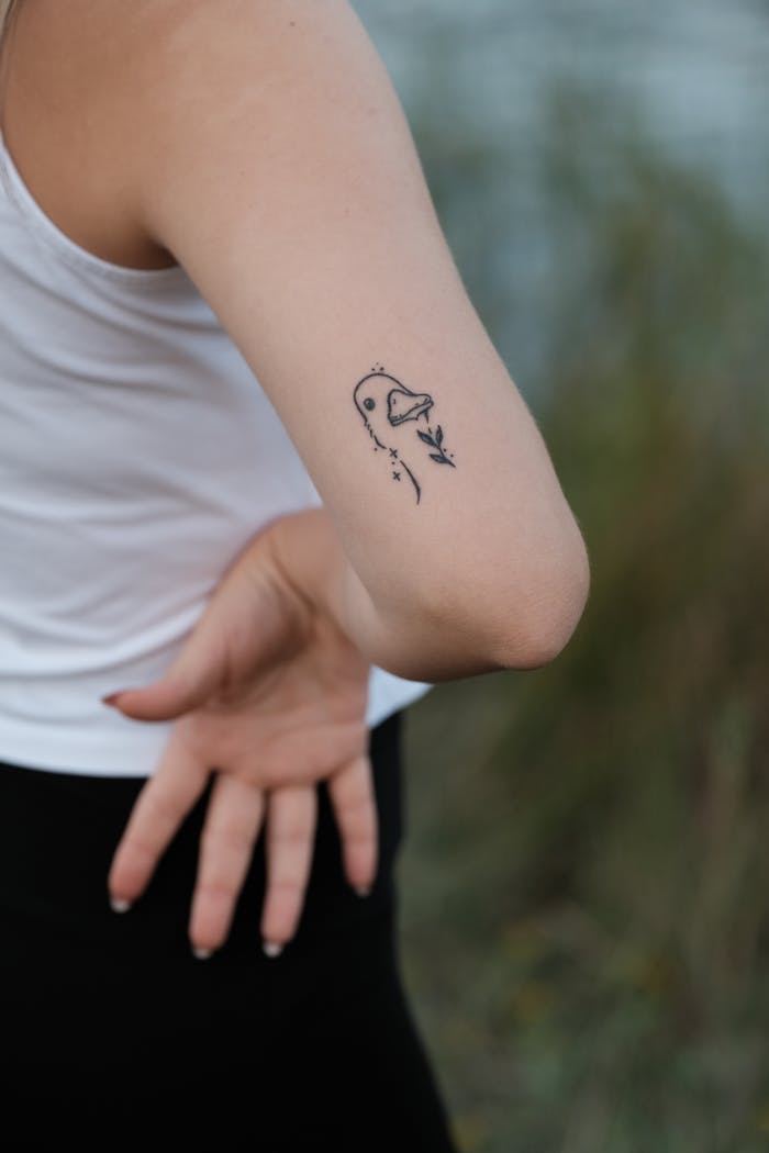 A close-up image focusing on a woman's arm with a minimalist tattoo design outdoors.